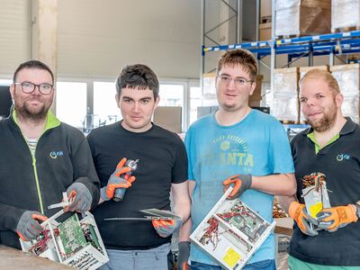 4 junge Männer halten Computerteile mit Sicherheitskleidung